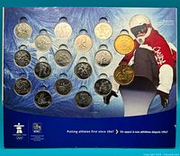Display folder with 17 commemorative coins arranged, including two gold-tone coins and fifteen silver-tone coins, with athlete decoration on the right.