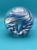 Front view of glass paperweight showing clear glass and blue-white spiral swirl design underpinning the top surface.