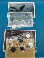 Photo showing two sealed Canadian coin sets from Royal Canadian Mint in original envelopes with certificates.