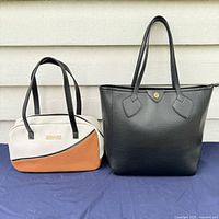 Two handbags side by side: a small white, tan, and black Kenneth Cole Reaction purse and a larger black tote handbag