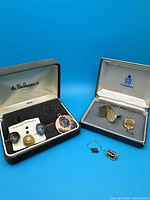 Photo showing all items in the lot, two presentation boxes with cuff links and pins, plus additional loose pins and a tie chain.
