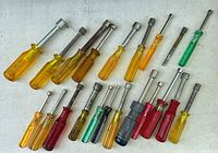 Top view of 20 assorted nut drivers with different colored translucent plastic handles in various sizes, organized on a white surface.