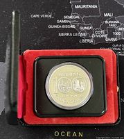 Oblique view of 1874-1974 Canadian silver commemorative coin in black display case lined with red velvet padding, highlighting the coin and case presentation