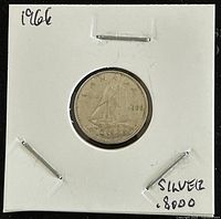 Front side of 1966 Canadian 10 cents coin showing Bluenose sailing ship and year 1966 clearly visible. Coin contained in a white fold-out sleeve with handwritten '1966' and 'silver .800'.