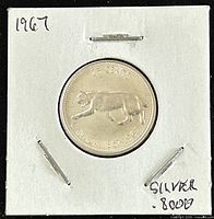 Reverse side of 1967 Canadian silver quarter featuring a walking cougar and the denomination.