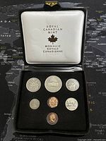 Photo showing seven Canadian coins in a black velvet case with white satin-lined lid labeled Royal Canadian Mint.