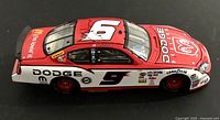 Side view of red and white 2005 Dodge Dealers NASCAR diecast car with number 9 and sponsor decals on a black background.