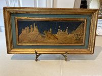 Full view of antique framed micromosaic picture with knight and castle scene and metal stand.