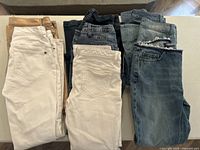 All eight pairs of ladies jeans folded, showing different colors and washes