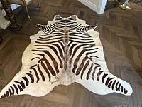 Full view of the faux tiger print carpet rug on wooden floor showing overall pattern and shape.