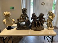 Four statues displayed on white table showing variety in size and style.