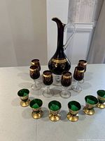 Full set view showing Persian glass decanter, six burgundy wine glasses, and six green liquor glasses arranged on countertop.