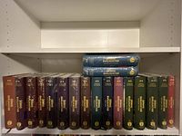Photo showing the full row of 18 Srimad Bhagavatam books with most books sealed and some opened but unused.