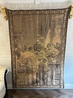 Full front view of tapestry hung on wall with gold brackets