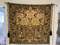 Full front view of tapestry hanging on gold-tone brackets with rope tassels