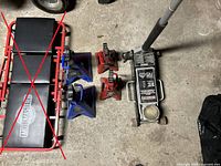 Full lot overview showing hydraulic jack and four jack stands; creeper crossed out (not included).