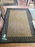 Full view of the olefin area rug showing overall pattern and condition on tile floor with furniture around.