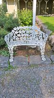 Front view of white cast iron bench on garden path