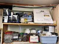 Shelf showing multiple Philips boxed light bulbs alongside jars with hardware screws and bolts, and small containers holding assorted items