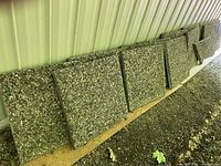Photo showing the full and half cement patio stones arranged upright against a wall. The stones have a speckled, textured aggregate finish.