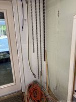 Photo showing lengths of chains and ropes hanging on wall, with some coils on floor, taken to document all chains and ropes in lot.
