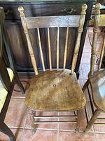 Front view of a vintage wooden dining chair showing carved backrest and spindle details.