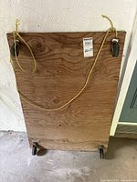 Photo of wooden dolly showing underside with wheels and yellow pull rope.