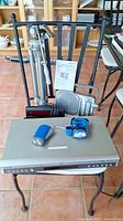 Full lot photo showing Toshiba DVD player on table, two flashlights on top, Panasonic receiver behind, Westcliff alarm radio, Gilyx tripod standing behind