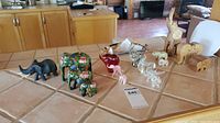 Full view of all elephant figurines displayed on a kitchen counter, showing variety in materials and sizes from glass to wood.