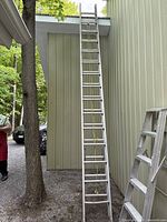 Full view of the ladder extended against a building showing its maximum reach.