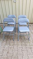 Front view of the four blue-gray folding chairs arranged in two rows showing cushioned seats and backs.