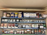 Four shelves packed with assorted hardware including screws in various packaging and some branded staple containers