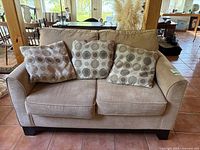 Front view showing loveseat with three circular printed accent pillows