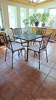 Full view of metal café table with four matching chairs positioned around it on tile floor