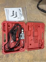 Milwaukee hammer drill and accessories in open red carrying case