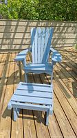Front view of light blue wooden Adirondack chair and matching foot stool on wood deck