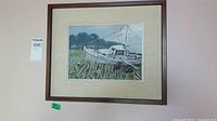 Original painting of a white boat grounded on shore with mountains and houses in the distance, matted and framed in wood.