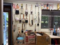 Overview of painting supplies including hanging brushes, boxes of supplies, paint cans, and filler tubes on counter.