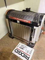Front view of Ridgid 13-inch thickness planer with manual on floor