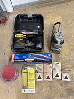 Full view of lot showing DeWalt orbital sander in case, Porter-Cable sander, Ryobi detail sander in box, and extra sandpaper sheets and discs.