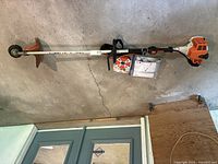 Full length view of FS 94 R trimmer against wall, showing debris guard and cutting head with wheel.