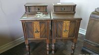 Front view of both vintage end tables side by side, showing matching design and wear on one top