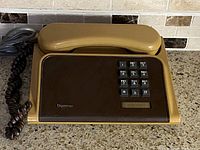 Vintage 1980s Northern Telecom Diplomat brown plastic push button phone shown on countertop, angled view showing handset, keypad, and branding.