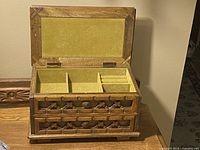 Jewelry box open showing yellow velvet lined interior compartments and two drawers.