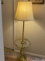Front view of the vintage brass floor lamp with round glass table and white lampshade, showing overall height and structure.