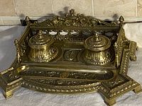 Front angled view showing dual round brass inkwell lids, ornate Victorian style casting, and tray details.