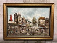 Front view of the framed oil painting showing the entire Paris street scene with Moulin Rouge and red windmill.