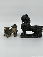 Front view showing both statues with one in smaller multicolored form and the other in larger dark form