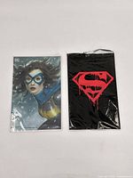 Batman comic book with Batgirl cover and Superman logo art item packaged in clear plastic sleeves
