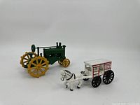 Front view of the green tractor and the horse-drawn carriage side by side